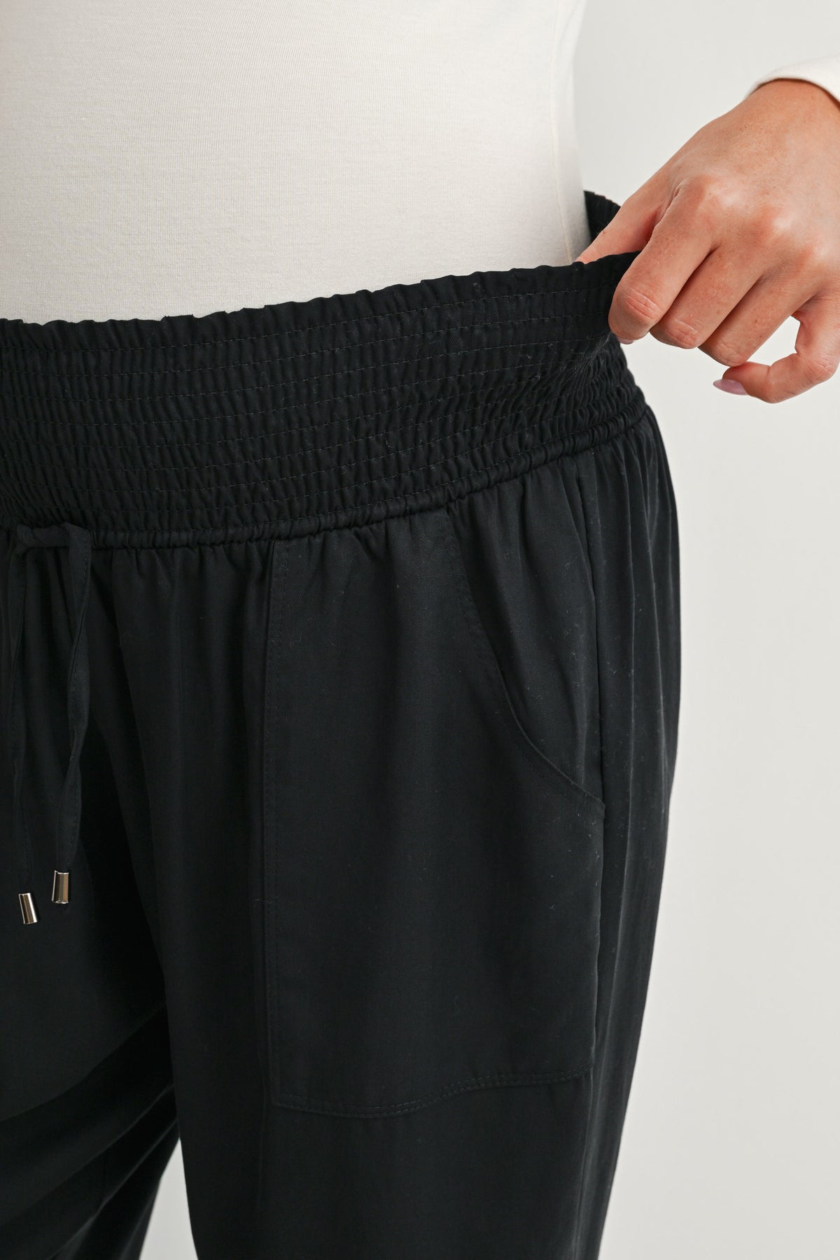 Close-up of black maternity jogger pants with stretchy smocked waistband and front pocket