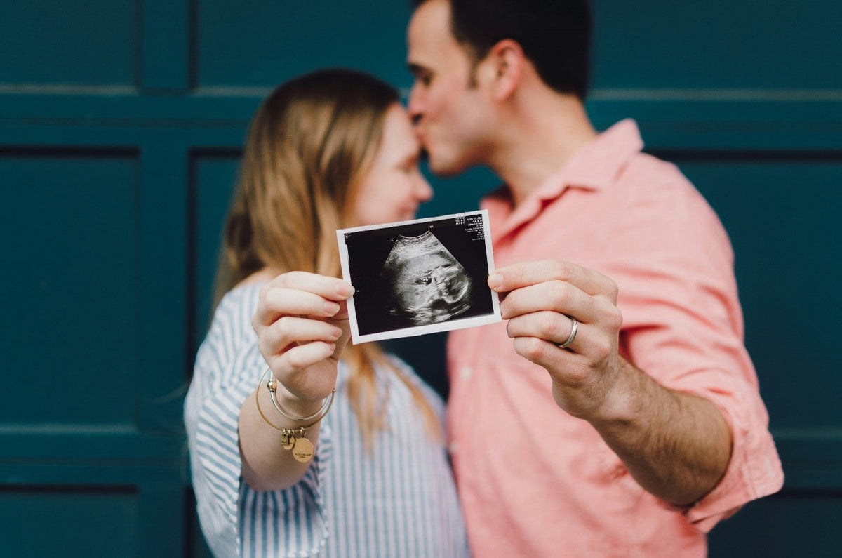 Pregnant couple holding an ultrasound scan during a pregnancy announcement photoshoot.